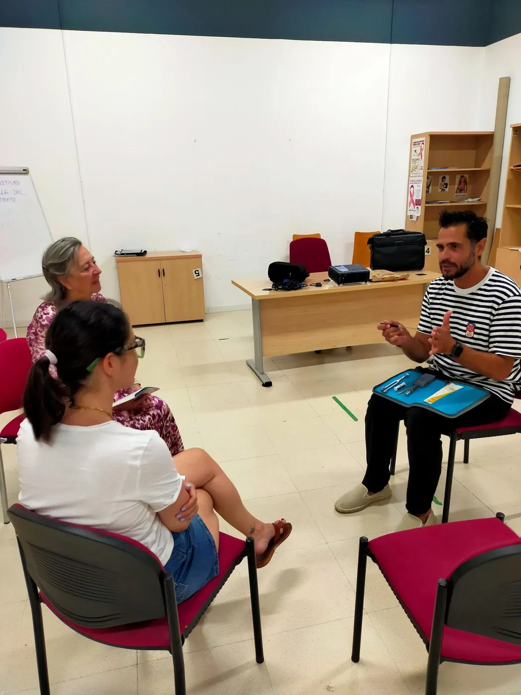 Dos asistentes conversan con el podólogo en la sala de la charla