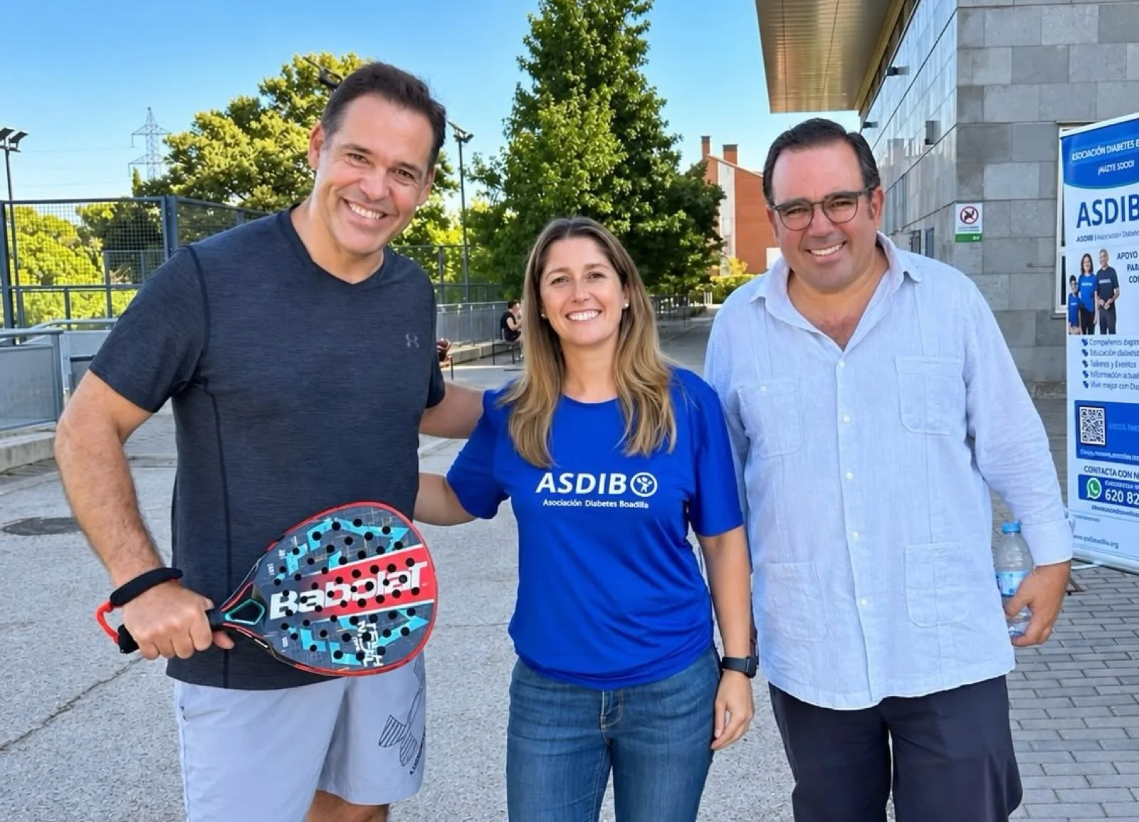 Miembros de la organización de ASDIBO junto a un jugador, con el banner de la asociación al fondo