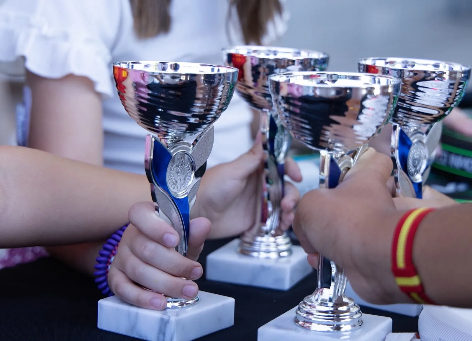 Manos de varios jugadores sujetando sus trofeos